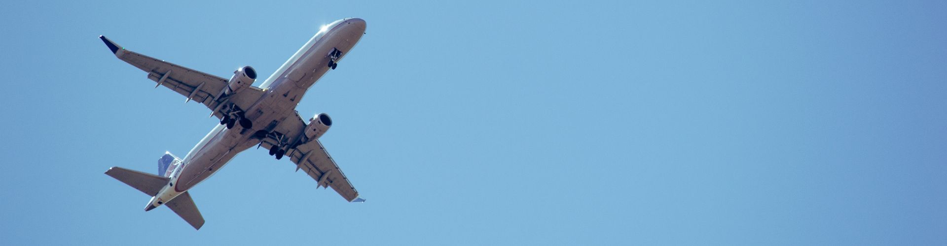 Commercial airplane flying overhead against a clear blue sky